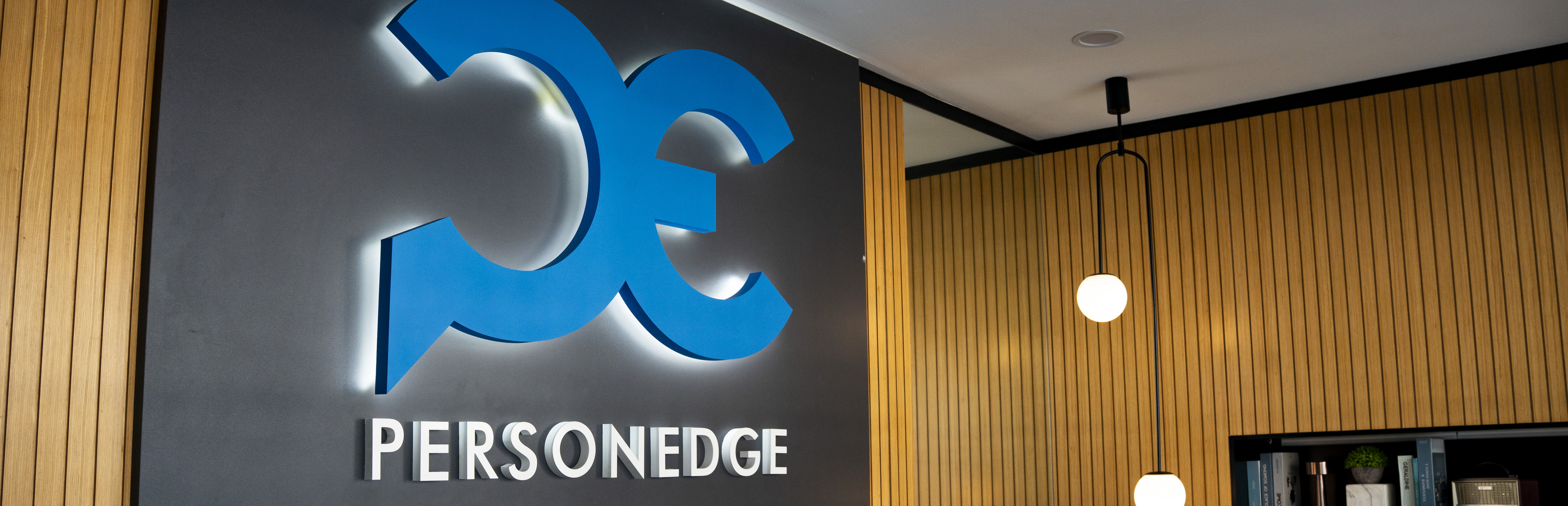 PersonEdge office reception with backlit logo on wood slats